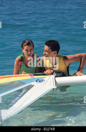Malediven. Vorderansicht des jungen Paares im Meer mit Surfbrett. Stockfoto