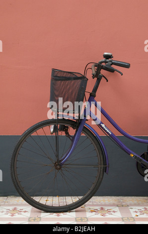 Vor einem alten Fahrrad mit Korb tragen, lehnte sich gegen die Wand Stockfoto
