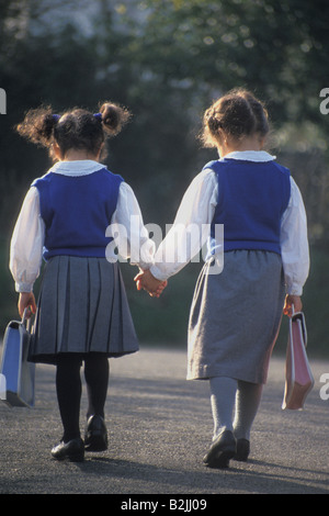 zwei kleine Mädchen in Schuluniform zu Fuß zur Schule Stockfoto