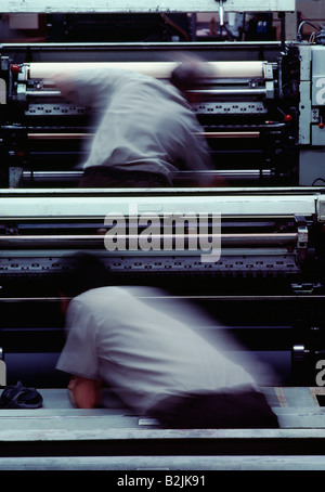 Zwei Pressman in einer Unschärfe der Aktion während der Arbeit an einem kommerziellen Offset-Druckmaschine Stockfoto