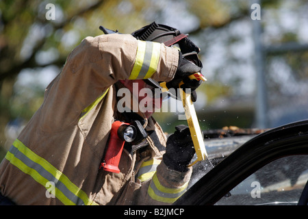 Ein Feuerwehrmann mit einem Glas Master Tool, um die Windschutzscheibe eines Autos, während Bergung eines Opfers schneiden Stockfoto