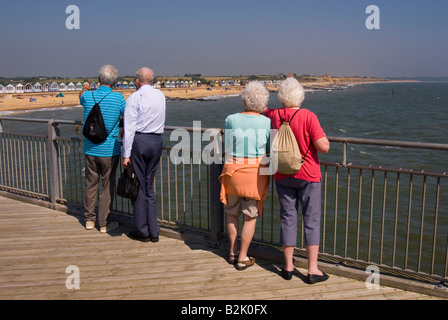 Menschen am Southwold Pier Look Out Over Strand an einem heißen Sommertag Stockfoto