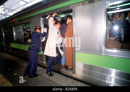 Menschen immer schob und schob in u-Bahn Zugtür während der Hauptverkehrszeit Tokio Stockfoto
