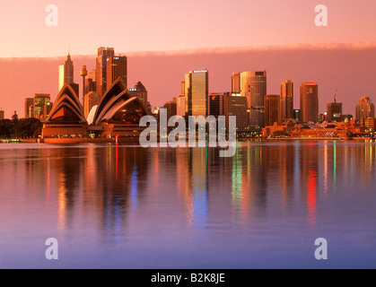 Hellen Sonnenaufgang reflektiert Skyline von Sydney mit Opernhaus reflektierenden über ruhigen Hafen Wasser Stockfoto