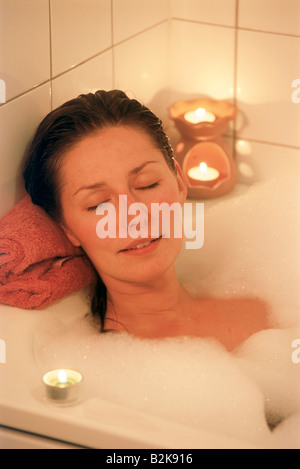 Frauen-Bad in der Badewanne mit Kerzen und Bläschen Stockfoto