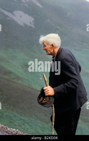 ÄLTERE MANN MIT GRAUEN HAAREN GEHEN WEG MIT HOLZSTAB PILGER IN CROAGH PATRICK S IRELAND Stockfoto