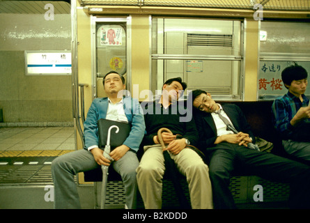 MÄNNER SCHLAFEN AUF EINEM BAHNHOF TOKIO JAPAN Stockfoto