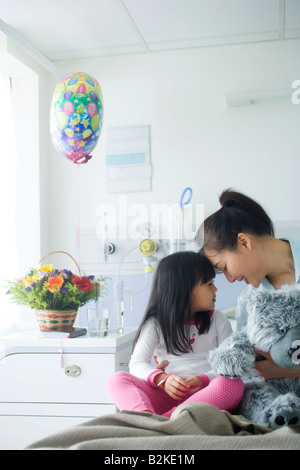 Mitte erwachsenen Frau hält einen Teddybär lächelnd mit ihrer Tochter Stockfoto