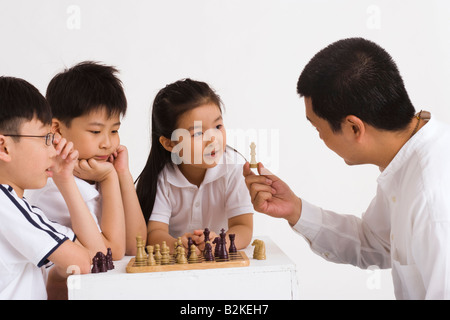 Mitte erwachsener Mann spielt Schach mit seinen Kindern Stockfoto