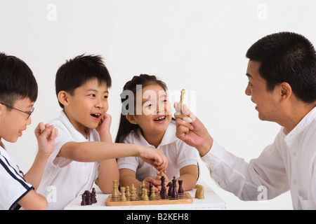 Mitte erwachsener Mann spielt Schach mit seinen Kindern Stockfoto