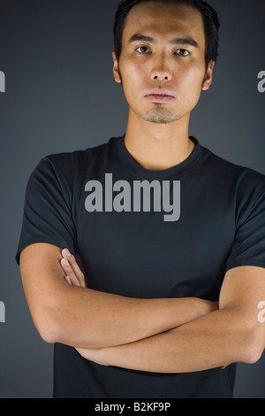 Porträt eines jungen Mannes Stand mit verschränkten Armen Stockfoto
