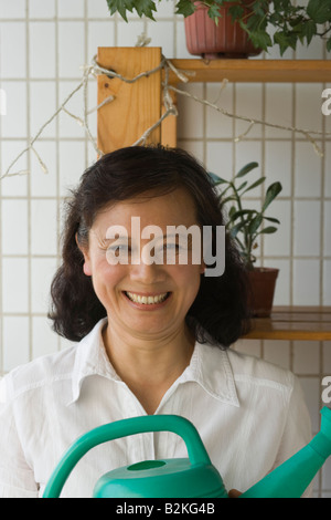 Porträt einer reifen Frau hält eine Gießkanne und lächelnd Stockfoto