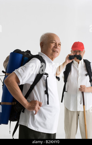 Seitenansicht eines älteren Mannes lächelnd mit seinem Freund Filmen im Hintergrund Stockfoto