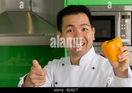 Porträt eines männlichen Chef hält eine gelbe Paprika und zeigt ein Daumen hoch Zeichen Stockfoto
