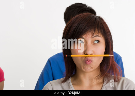 Nahaufnahme einer jungen Frau, die Bilanzierung eines Bleistifts auf den Lippen Stockfoto