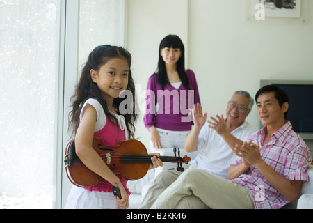 Familienangehörige, die eine Mädchen spielt Geige zu schätzen Stockfoto