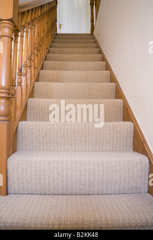 Blick auf eine Treppe mit glatten Treppe Teppich auf der Treppe und eine hölzerne Geländer gesehen von unten in einem Haus. Großbritannien Großbritannien Stockfoto