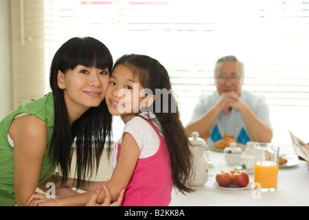 Nahaufnahme einer Mitte erwachsenen Frau lächelnd mit ihrer Tochter auf einem Frühstückstisch Stockfoto
