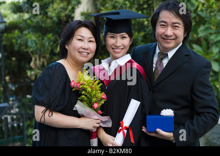 Porträt der weiblichen Absolventen Diplom und stehen mit ihren Eltern Stockfoto