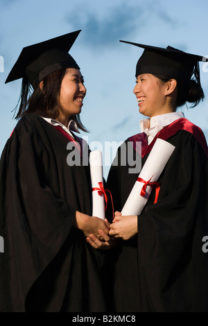 Zwei weibliche Absolventen hält Diplome und lächelnd Stockfoto