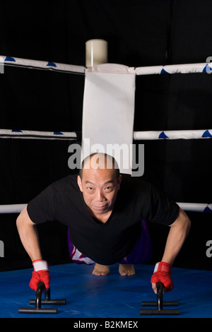 Reifer Mann mit Push-up-Bars in einem Boxring Ausübung Stockfoto