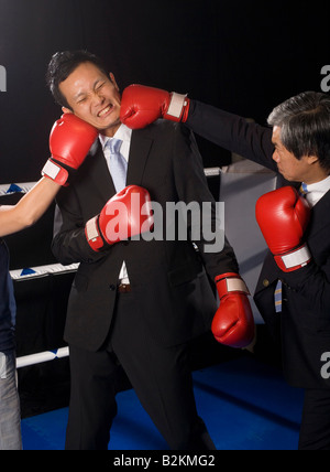 Durch seine zwei Gegner in einem Boxring Geschäftsmann Stockfoto