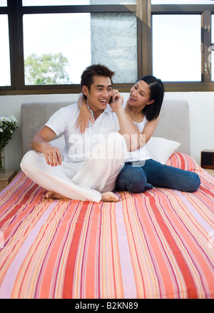Junger Mann im Gespräch auf ein Mobiltelefon und eine Mitte Frau neben ihm zu sitzen Stockfoto