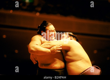 Sumo-Ringer mit schmerzte Ausdruck auf seinem Gesicht, als er um den Körper von Gegner im Kampf Japan packte ist Stockfoto