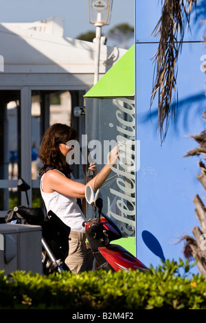 Frau macht einen Anruf in einer öffentlichen Telefonzelle der spanische Telekom-Anbieter Telefonica in Cala Ratjada, Mallorca, Spanien Stockfoto