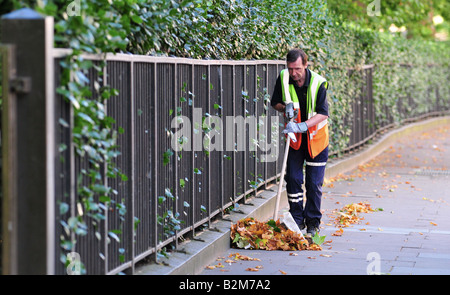 Eine einsame Straße-Cleaner fegt die Blätter, die auf den Bürgersteigen von Mayfair, London gefallen war. Stockfoto