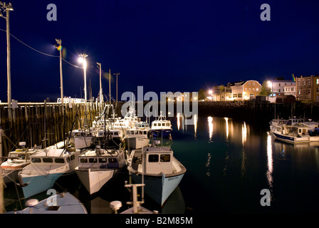 Viele Fischerboote zu Docks in einer Sommernacht mit Lichter Reflexion im Wasser gebunden. East Port Maine Stockfoto