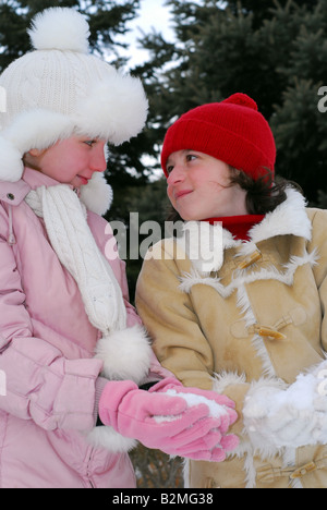 Porträt von zwei kleinen Mädchen in Winter Park holding Schneebälle Stockfoto