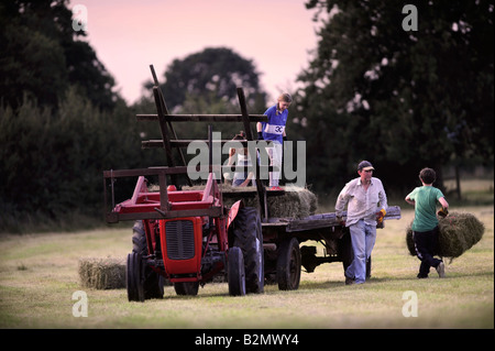 EINE BAUERNFAMILIE SAMMELN HEU IM TRADITIONELLEN STIL IN GLOUCESTERSHIRE UK Stockfoto