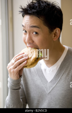 Porträt eines jungen Mannes einen Hamburger Essen Stockfoto