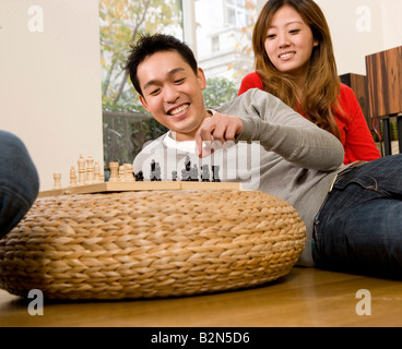 Ein fröhliches junges Paar spielt Schach Stockfoto