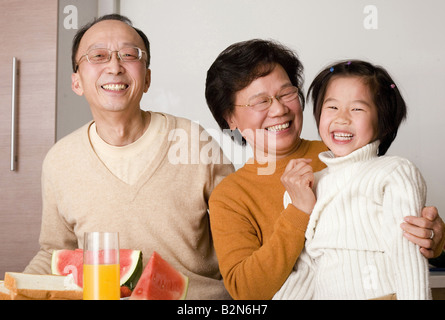 Ein älteres Paar mit ihrer Enkelin am Frühstückstisch sitzen in Nahaufnahme Stockfoto