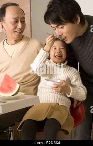 Nahaufnahme eines Mädchens Fütterung ihres Vaters und ein senior Mann sitzt neben Ihnen Stockfoto