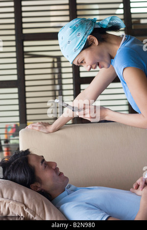 Seitenansicht einer jungen Frau, die ein Bild eines jungen Mannes mit einem Mobiltelefon Stockfoto
