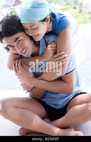 Junge Frau, die einen jungen Mann von hinten umarmen Stockfoto