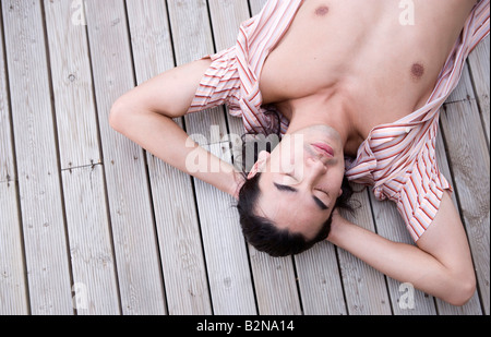 Erhöhte Ansicht eines jungen Mannes Nickerchen auf einem Holzbrett, Phuket, Thailand Stockfoto