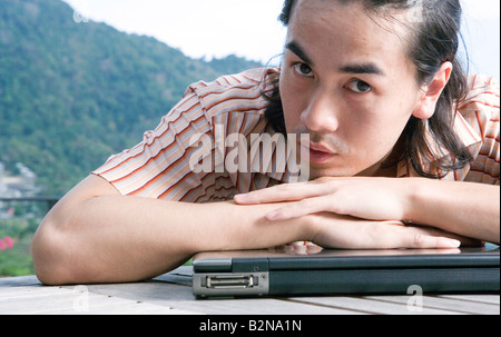 Porträt eines jungen Mannes stützte sich auf einen Laptop, Phuket, Thailand Stockfoto