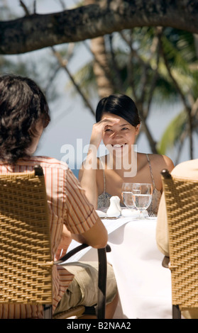 Junge Frau mit ihren Freunden am Esstisch sitzen und Lächeln, Phuket, Thailand Stockfoto