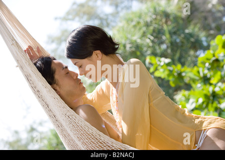 Seitenansicht eines jungen Paares romancing in einer Hängematte, Phuket, Thailand Stockfoto