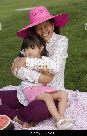 Ältere Frau umarmt ihre Enkelin auf einer Picknickdecke Stockfoto