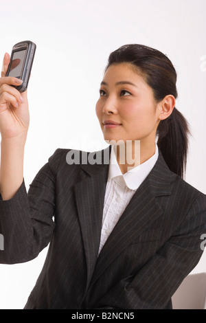 Geschäftsfrau mit Blick auf ihr Handy und lächelnd Stockfoto