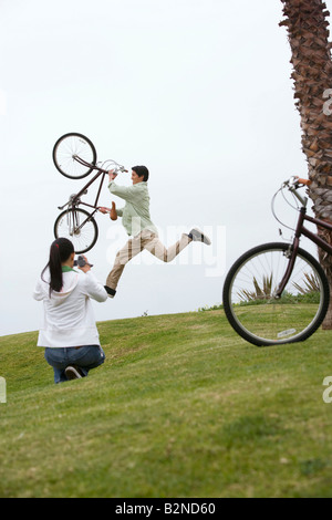 Rückansicht einer jungen Frau, die Dreharbeiten Mitte erwachsenen Mannes ausführen einen Stunt mit dem Fahrrad, Huntington Beach, Kalifornien, USA Stockfoto
