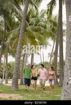 Zwei Paare, die zu Fuß am Strand mit halten einander die Hände Stockfoto