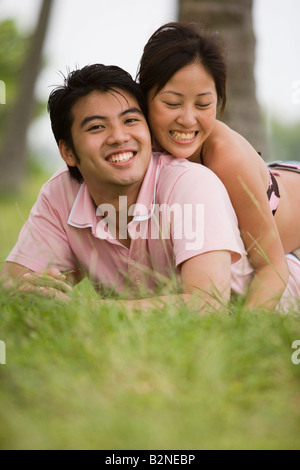 Junge Frau liegend auf einem jungen Mann lächelnd Stockfoto