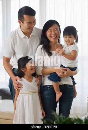 Mitte erwachsenes paar stehen mit ihren beiden Töchtern in einem Wohnzimmer, Singapur Stockfoto