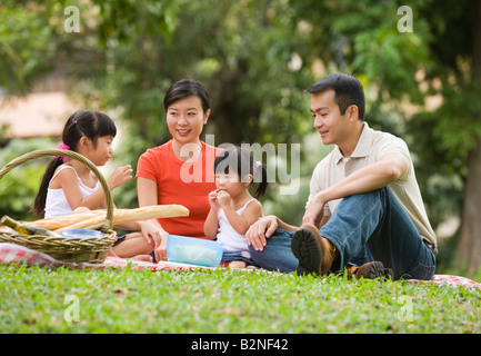 Mitte erwachsenes paar mit ihren beiden Töchtern mit Picknick in einem Park, Singapur Stockfoto
